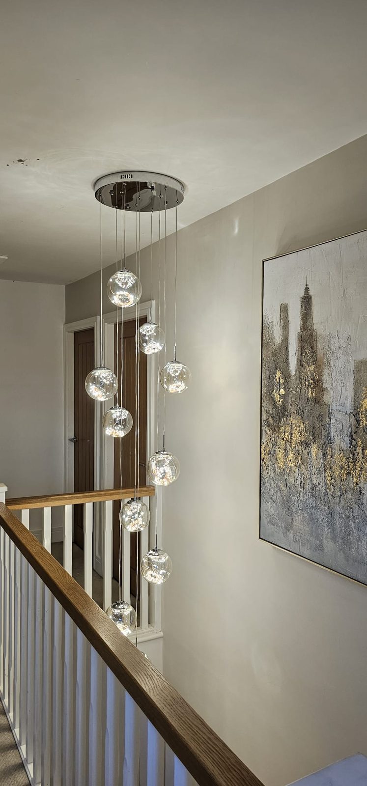 Cascading glass orb pendant light hanging over a staircase, installed by Z Electricals